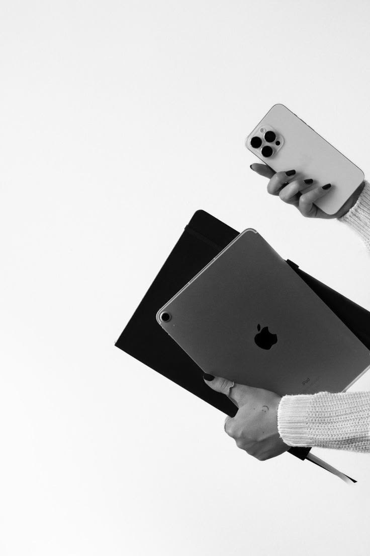 Hands holding a phone, tablet, and notebook